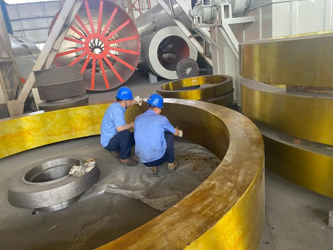 Two technicians in blue helmets checking a large metal ring